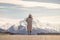 A boho hippy lady in white dress with hat stands on road with aoraki snow mountain background in New Zealand. idea for travel, de