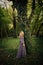 Boho style woman stand by huge tree in wood summer day