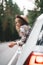 Boho woman sitting in car looking from window on beautiful view in country road. Lifestyle concept