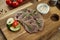 Boiled beef tongue with sauce and vegetables on a wooden board. Appetizing appetizer. Delicacy