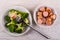 Boiled broccoli in plate, bowl with sausages, fork on table. Top view