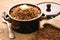 Boiled buckwheat porridge in ceramic pot on wooden background.