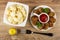 Boiled cauliflower in bowl, ketchup in sauceboat with handle, chicken cutlets, basil in white plate, pepper shaker, fork on wooden