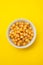 Boiled chick pea in white bowl on yellow background