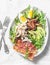 Boiled chicken, avocado, egg, arugula, kumato tomato, bacon salad on a light background