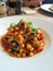 Boiled chickpeas with tomato, eggplant and leaf on plate.