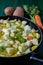 Boiled cod with potatoes, celery and carrots. Close-up of pan ready to cook, on green wooden background