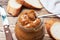 Boiled condensed milk with a glass jar on a wooden background. Sweet paste spread on slices of bread for Breakfast and dessert