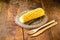 Boiled corn cob, on a rustic wooden table, with recycled wood graphs, bamboo forks