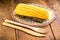 Boiled corn cob, on a rustic wooden table, with recycled wood graphs, bamboo forks