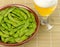 Boiled edamame in a bowl with a glass of beer