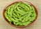 Boiled edamame, green soybeans in bowl on bamboo mat
