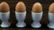 Boiled eggs in egg cups on a wooden table to one that has been broken open ready to eat