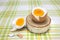 Boiled fresh egg for the breakfast on the wooden birch stand for eggs. Broken beige hen egg and pieces of shells, bright orange yo