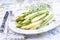 Boiled green and white Asparagus offered on a bone China porcelain plate on a well-laid table