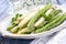 Boiled green and white Asparagus offered on a modern design art plate on a well-laid table