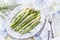 Boiled green and white Asparagus offered on a traditional bone China porcelain plate on a well-laid table