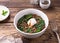 Boiled lentils with spinach, herbs, spices and poached egg in ceramic bowls on a wooden background