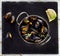 Boiled mussels in cooking dish on dark background.
