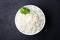 Boiled rice in a bowl on black stone background