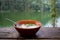 Boiled Rice with Pork and vegetable in black bowl on wooden table with river view