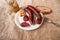 Boiled sausage on white plate, horseradish with apple, fork and sliced bread on rural jute tablecloth, closeup