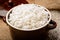 Boiled white rice in ceramic pot on wooden background.