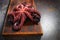 Boiled whole octopus on a wooden cutting board. Whole carcass of an octopus. Cooking seafood dishes. Dark background. Protein food