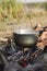 Boiling cauldron is on an open fire, camping meal