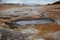 Boiling mudpots in the geothermal area Hverir and cracked ground around, Iceland in summer. Myvatn region, North part of Iceland