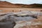 Boiling mudpots in the geothermal area Hverir and cracked ground around with unrecognisable tourists, Iceland in summer. Myvatn