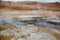 Boiling mudpots in the geothermal area Hverir and cracked ground around with unrecognisable tourists, Iceland in summer. Myvatn