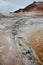 Boiling mudpots in the geothermal area Hverir and cracked ground around with unrecognisable tourists, Iceland in summer. Myvatn