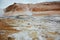 Boiling mudpots in the geothermal area Hverir and cracked ground around with unrecognisable tourists, Iceland in summer. Myvatn