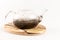 Boiling water is poured into a glass teapot with aromatic herbal tea standing on a wooden stand on a white background