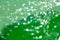 Bokeh blurred thin sheet of green colour cellophane with shiny crumpled surface texture on white background, Abstract, Light &