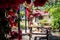 Bokeh of lovely colorful outdoor pub's backyard full of red flowers hanging from a pergola on a bright sunny day