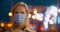 Bokeh shot of mature woman with surgical mask in evening city