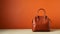 Bold And Graceful Brown Leather Handbag On Orange Wall