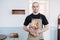 Bold male baker holding paper bag with fresh baguettes