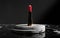 A bold, scarlet-hued lipstick stands poised atop a striking black and marble pedestal, exuding an air of regality and