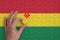 Bolivia flag is depicted on a puzzle, which the man`s hand completes to fold