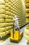 BOLOGNA , ITALY - MAY 02, 2018: Worker inspecting cheese in Parmigiano Cheese factory. Shelves with aging cheese in Italy, Bologna