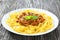 Bolognese ragout with italian pasta on a white plate, close-up