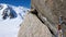 Bolt and quick draw with climbing equipment on an exposed and steep climbing route in the French Alps with Mont Blanc in the backg