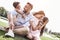 Bonding. Family of four sitting on a grassy field hugging laughi