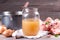 Bone Broth in a glass jar, bones and fresh vegetables, garlic cloves and herbs on table, paleo diet