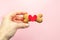 Bone-shaped biscuit for dog and red heart in woman hand on pink background, concept pet care.