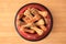 Bone shaped dog cookies in feeding bowl on wooden table, top view