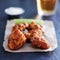 Boneless barbecue chicken wings with beer on slate surface